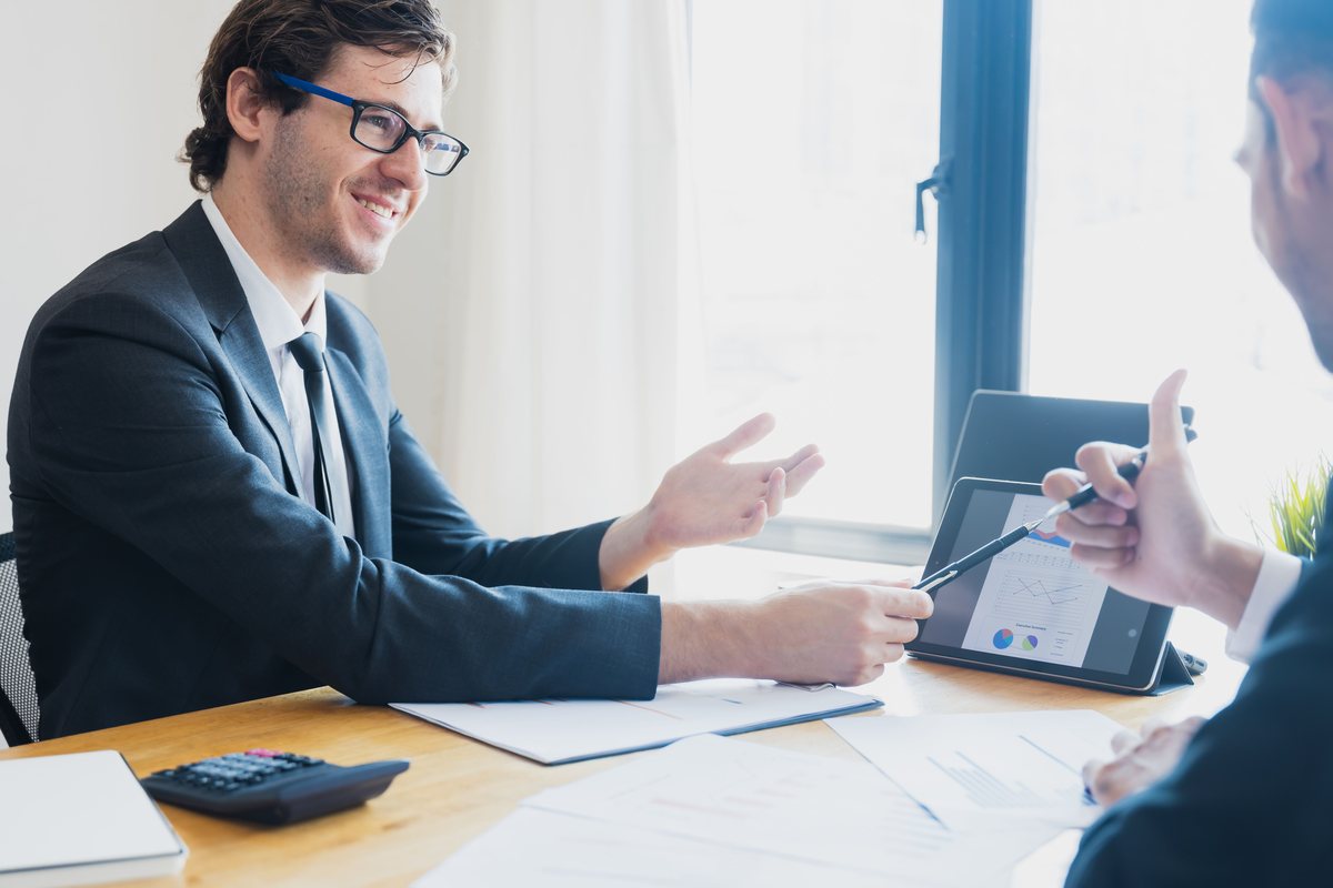 Consultor apresentando análise financeira em tablet durante reunião com cliente